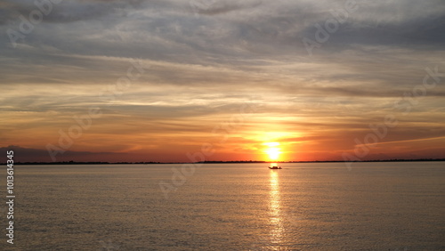 Fototapeta Naklejka Na Ścianę i Meble -  sunset over the river, a boatman's silhouette is seen riding his boat.