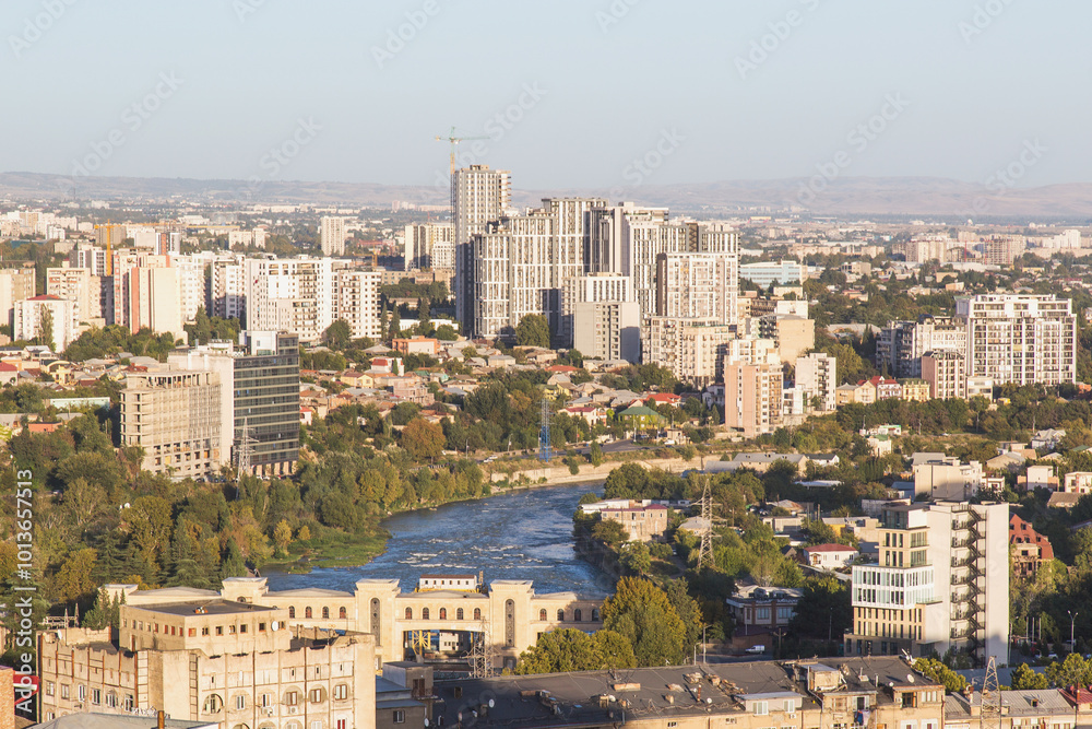 Naklejka premium unpopular view of Tbilisi city center capital of Georgia, residential buildings, construction site and Ortachala hydroelectric power station on the Kura River