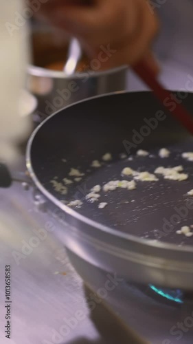 Vertical footage of Chef Frying Garlic with Rosemary In Oil On Non-stick Pan.