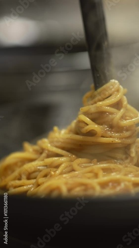 Verticla footage of Chef making fresh spaghetti pasta using a different technique, Young white guy placing freshly cooked spaghetti pasta into a bowl. Italian cooker making pasta for lunch. photo