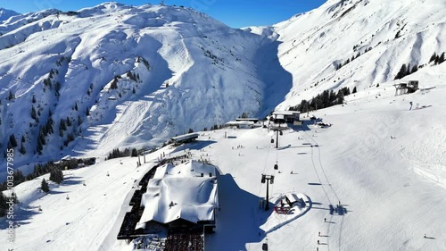 St Anton am Arlberg, Austria: Aerial view of famous bustling ski resort in Tyrolean Alps. Snow-covered slopes with ski runs, sunny day with clear blue sky - landscape panorama of Europe from above
 photo