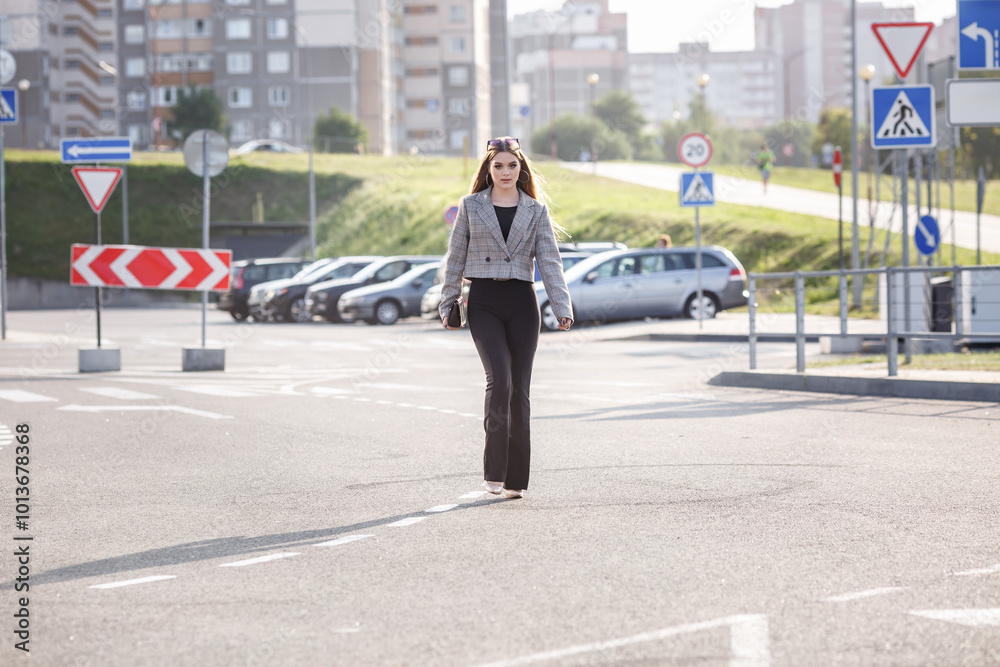 young girl with sunglasses in jacket posing near modern office building with mirrored walls in parking lot with road signs young girl with sunglasses in jacket posing near modern office building with mirrored walls in parking lot with road signs