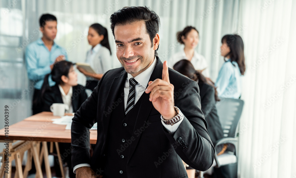 Portrait of happy businessman looking at camera, making finger pointing gesture for advertising product with motion blur background of business people movement in dynamic business meeting. Habiliment Portrait of happy businessman looking at camera, making finger pointing gesture for advertising product with motion blur background of business people movement in dynamic business meeting. Habiliment