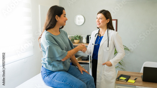 Obraz na plátně Female doctor smiling and shaking hands with her hispanic patient after a consul