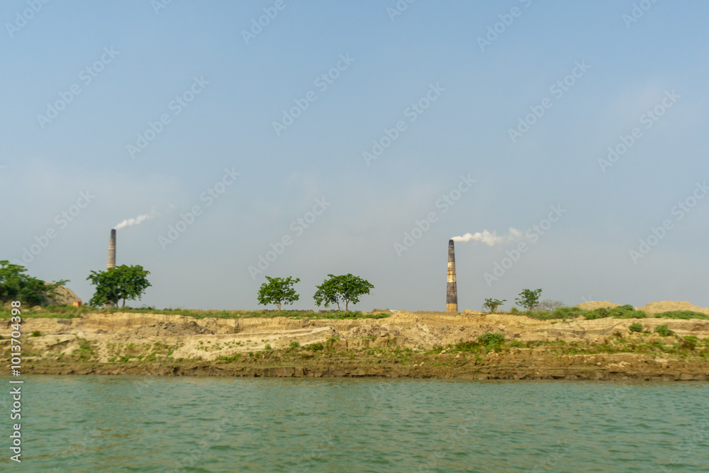 Smoking chimneys of brick factory on banks of Ganges (Padma) River, Bangladesh.