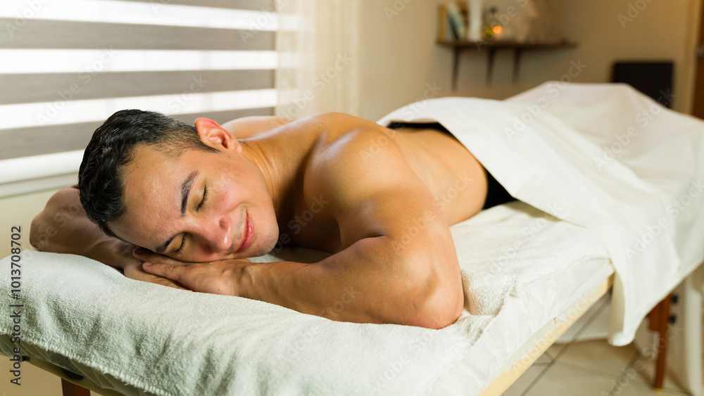 Good looking man lying on a massage table with his eyes closed, enjoying a relaxing spa treatment Good looking man lying on a massage table with his eyes closed, enjoying a relaxing spa treatment