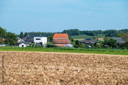 Plowed agriculture fields and houses at the Flemish countryside in Bekkevoort, Flemish Brabant, Belgium photo