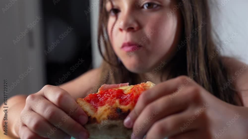 Young girl holding a slice of pizza, looking intently at the food while sitting at a table indoors, capturing a moment of savoring her favorite dish in a close-up view Young girl holding a slice of pizza, looking intently at the food while sitting at a table indoors, capturing a moment of savoring her favorite dish in a close-up view