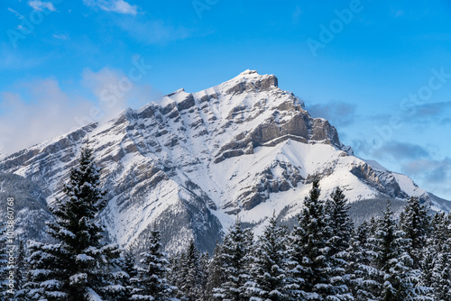 Close up snow-covered Cascade Mountain with snowy forest over blue sky and white clouds in winter sunny day. Banff National Park beautiful landscape. Canadian Rockies, Alberta, Canada. photo