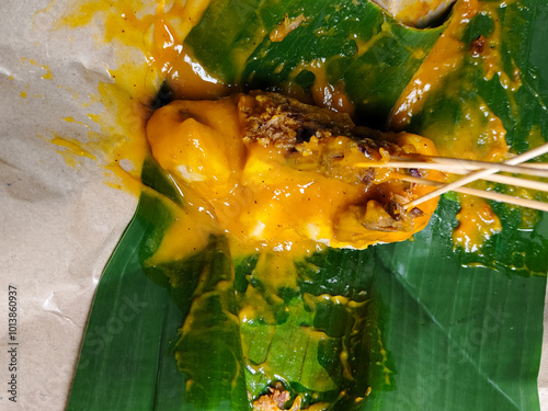 close up of eating satay wrapped in banana leaves photo