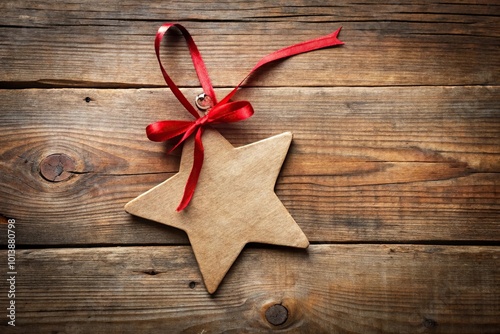 Blank star shape paper Christmas gift tag with red ribbon on rustic wood background