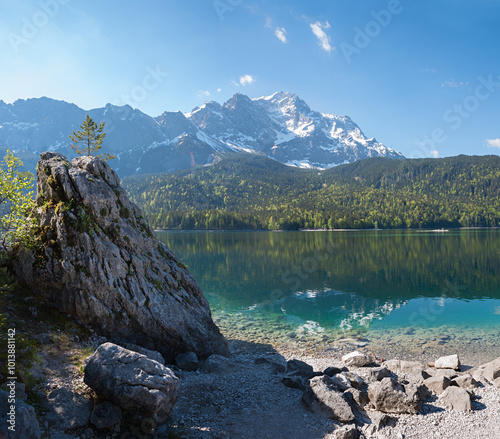 big rock with small conifer at lakeside Eibsee, view to Zugspitze mountain, bavaria photo