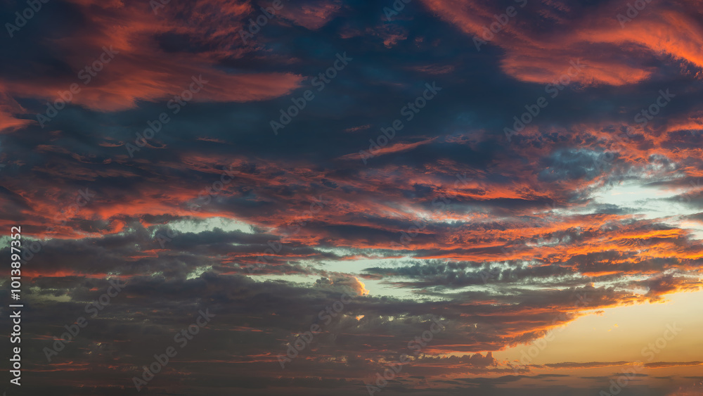 Fototapeta premium Panoramic view of a dramatic sunset sky with vibrant orange and deep blue clouds.
