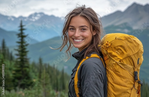 Smiling woman with a yellow backpack standing in a lush mountain landscape, radiating joy and adventure, ready for a hiking journey in nature's embrace.