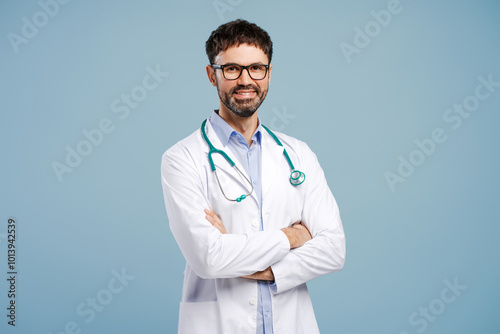 Attractive doctor with arms crossed wearing white coat and stethoscope isolated on blue background