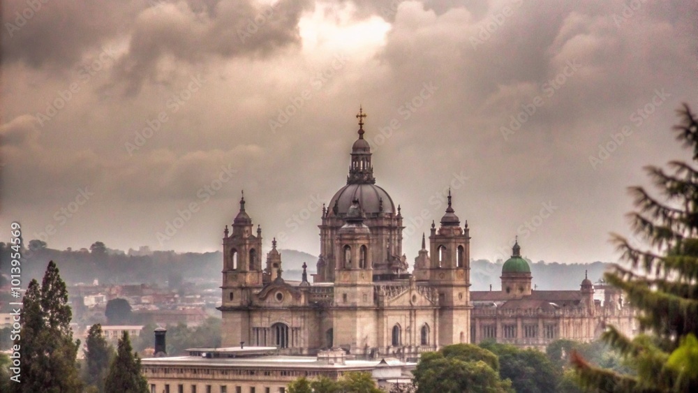 Naklejka premium A large cathedral with a dome and a cross on top, against a cloudy sky, surrounded by trees and buildings.