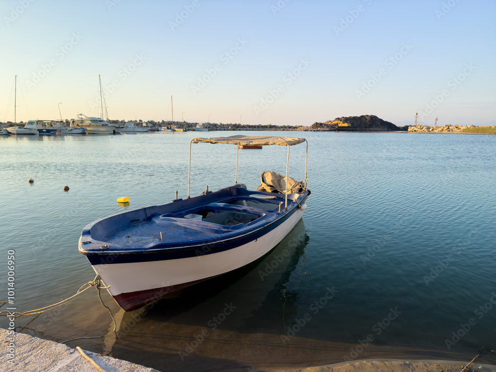 A Tranquil Fishing Boat Rests in Calm Waters During Sunset Near a Serene Coastal Harbor