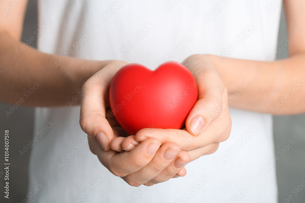 Woman holding red heart on grey background, closeup Woman holding red heart on grey background, closeup
