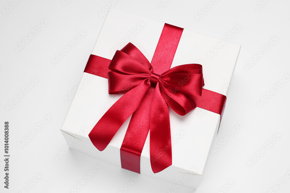 Gift box with red bow on light grey background, above view Gift box with red bow on light grey background, above view