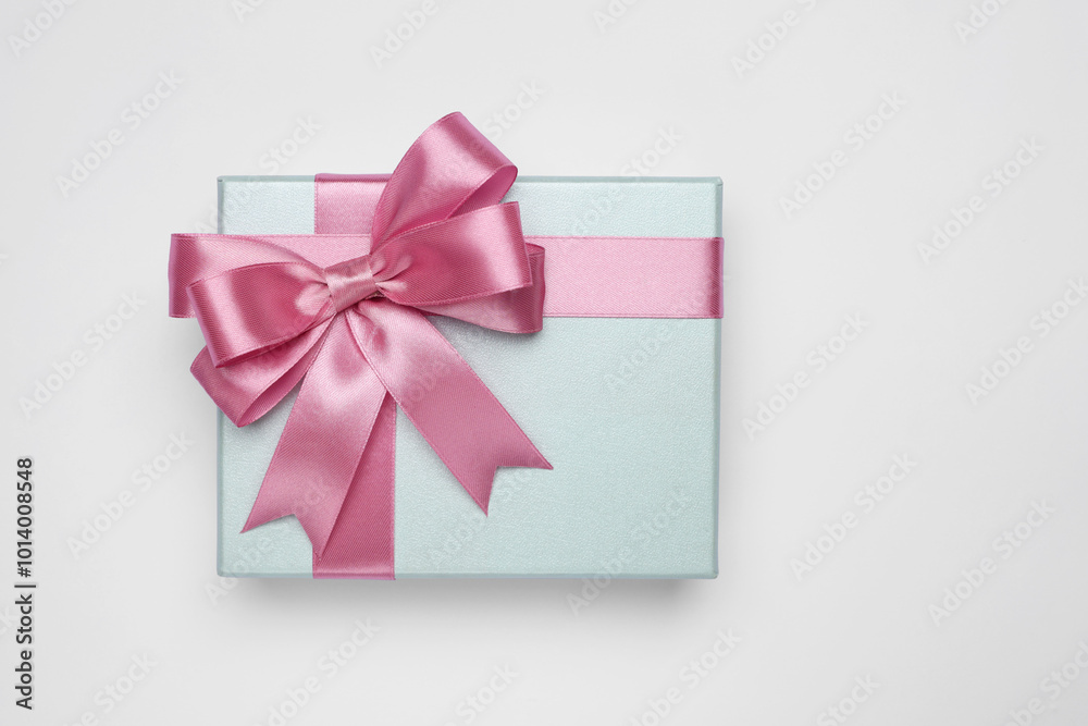 Gift box with pink bow on light grey background, top view Gift box with pink bow on light grey background, top view