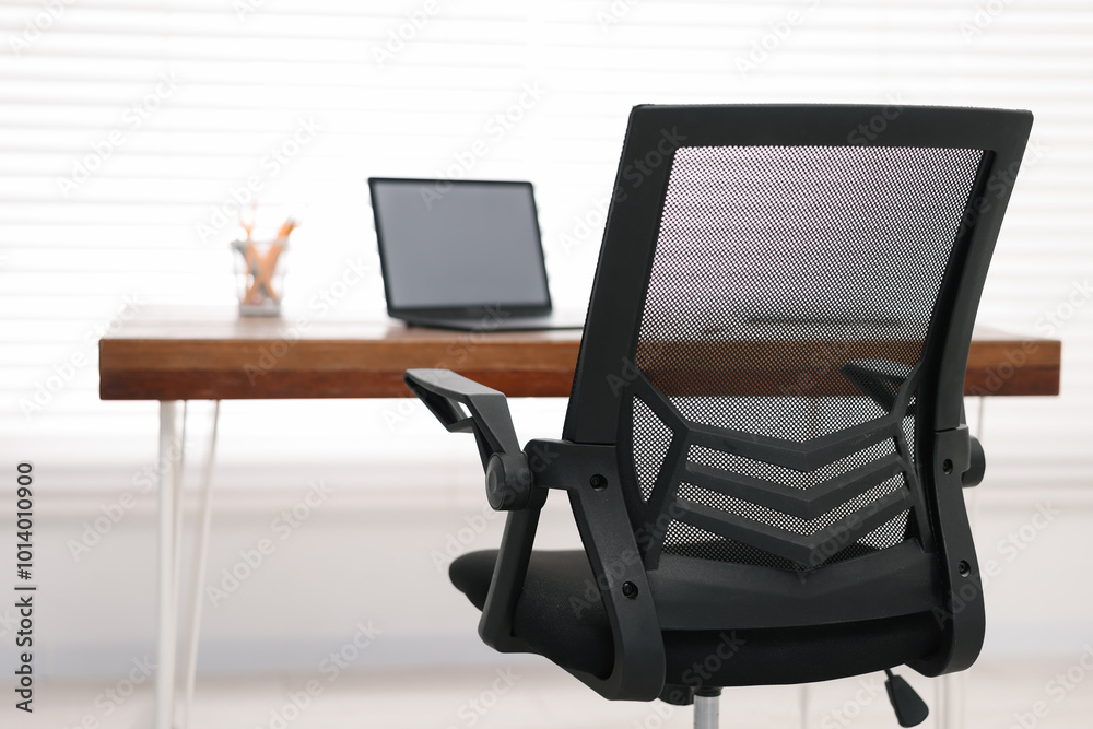 Fototapeta premium Black chair, laptop and desk in office, closeup