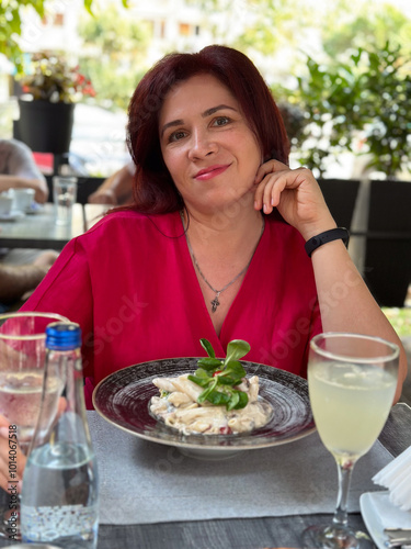 Woman enjoying a refreshing drink at an outdoor cafe in a vibrant setting. Relaxation and the joy of savoring a leisurely afternoon