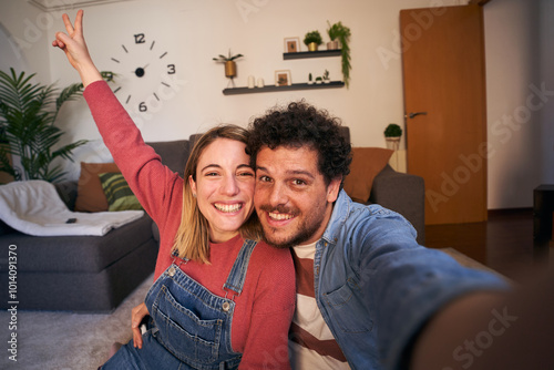 Fotografía Joyful young adult Caucasian couple taking selfie looking smiling at camera at home