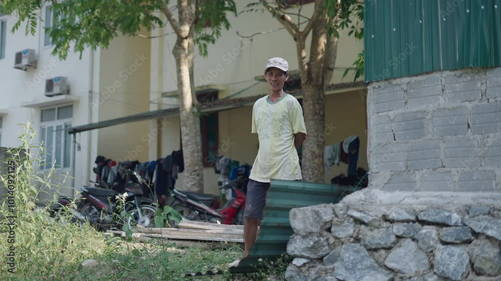 asian vietnamese man with cap standing looking and smiling at camera next to a building asian vietnamese man with cap standing looking and smiling at camera next to a building