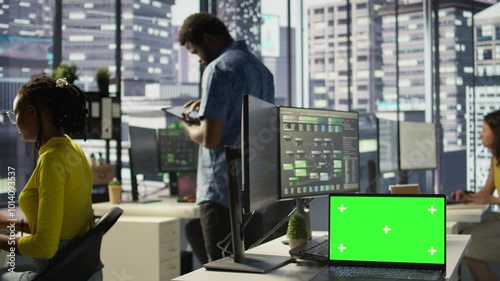 Wallpaper Mural Green screen laptop on desk in workspace with admins in background doing software quality assurance. Chroma key notebook in office with woman at work inspecting coding on device, camera B Torontodigital.ca