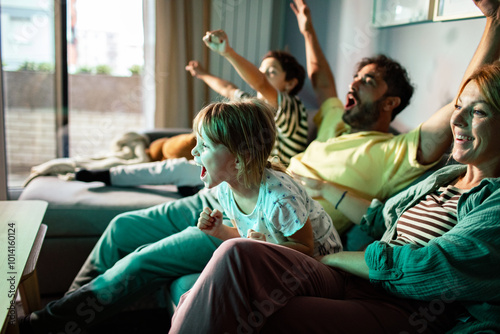 Excited family watching TV and cheering on the couch
