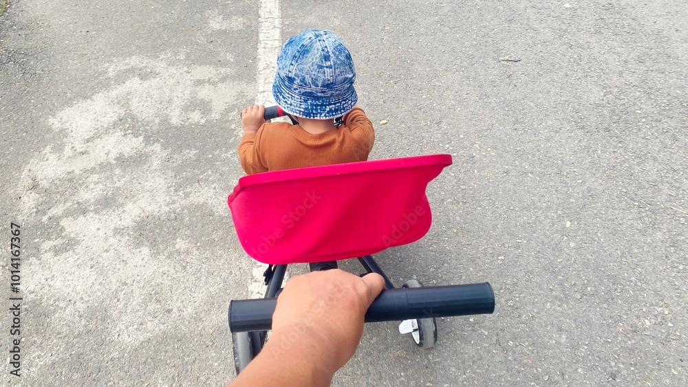 Naklejka premium A heartwarming scene of a father pushing his son on a bike, capturing the bond between a dad and his child.