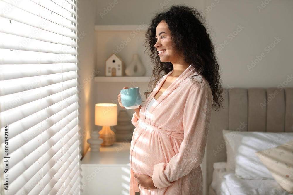 Portrait of beautiful pregnant with cup of drink near window at home Portrait of beautiful pregnant with cup of drink near window at home