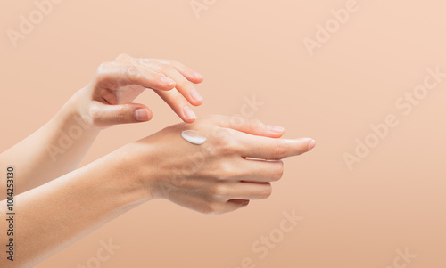 Woman hand applying cosmetic cream on her finger on background.