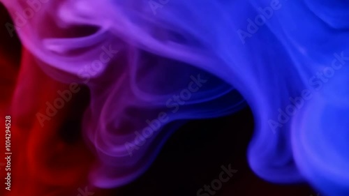 Abstract swirls of vibrant red and blue smoke blend together creating a smooth flowing texture. The deep contrasting hues form an ethereal dreamlike atmosphere.