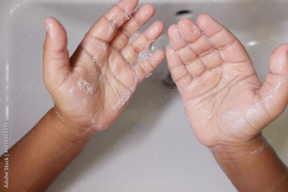 Fototapeta premium child making a cleansing gesture with soap and water on hands