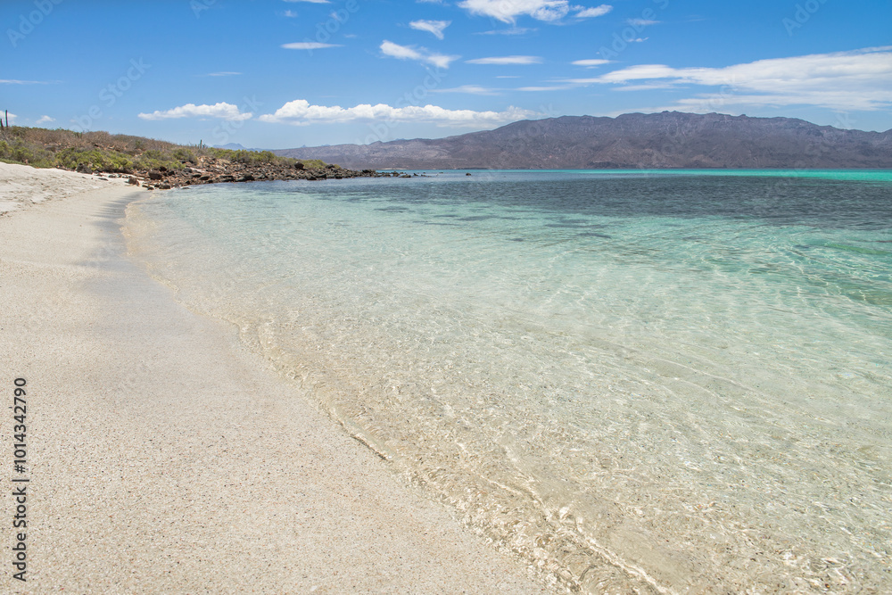 Clean and crystal clear waters on Isla Coronado beach in Loreto Baja California Sur Mexico, summer vacation on a sunny morning with mountains and blue sky in the background Clean and crystal clear waters on Isla Coronado beach in Loreto Baja California Sur Mexico, summer vacation on a sunny morning with mountains and blue sky in the background