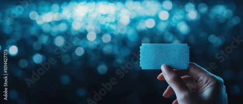 Hand holding a blue ticket against a blurred background with bokeh effect. photo