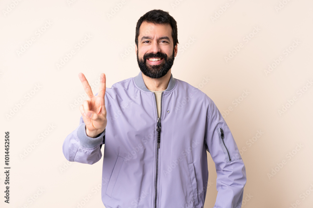 Caucasian man with beard wearing a jacket over isolated background smiling and showing victory sign Caucasian man with beard wearing a jacket over isolated background smiling and showing victory sign