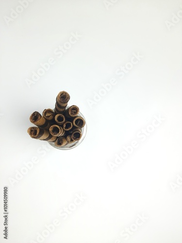 wafer rolls with chocolate in jar and plate on isolated white background