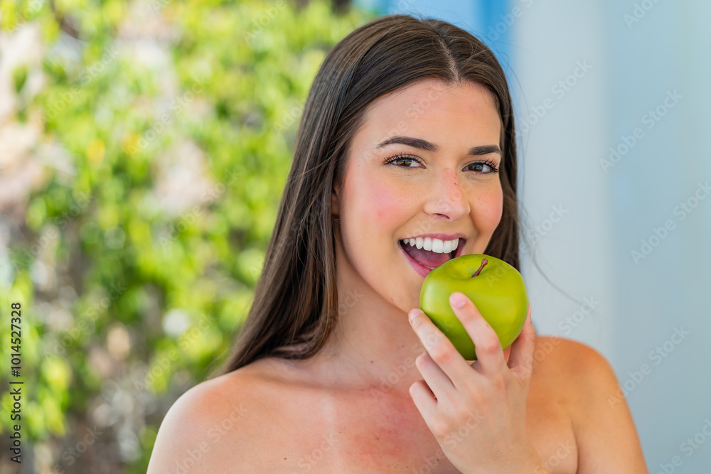 Young pretty Brazilian woman at outdoors holding an apple Young pretty Brazilian woman at outdoors holding an apple