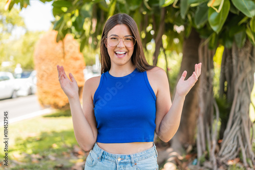 Young pretty Brazilian woman with glasses at outdoors smiling a lot photo