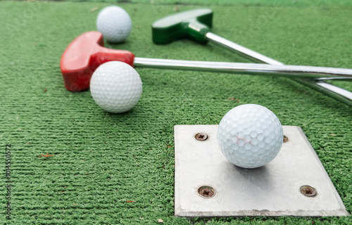 Mini golf. A club and a white ball on a golf course. photo