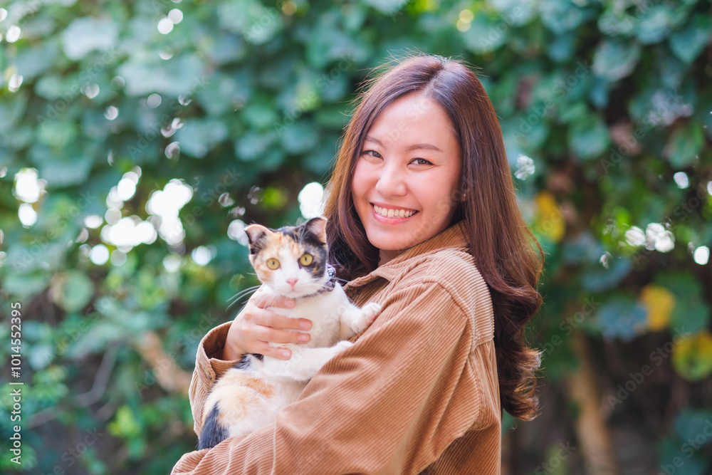 A woman holding a little black and white color cat in the outdoors A woman holding a little black and white color cat in the outdoors