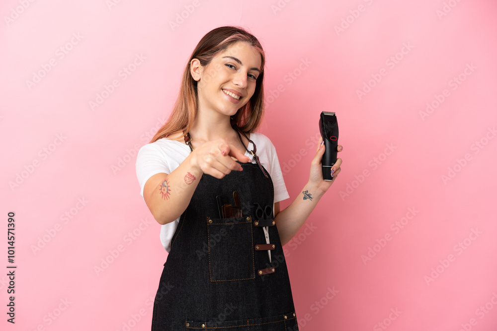 Young hairdresser woman isolated on pink background pointing front with happy expression Young hairdresser woman isolated on pink background pointing front with happy expression