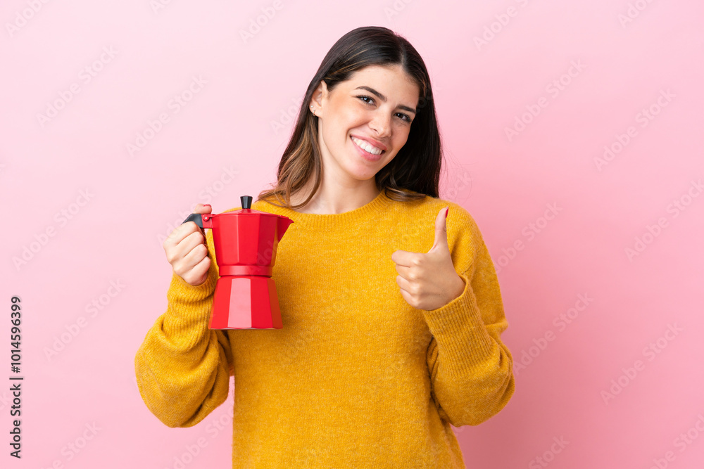 Young Italian woman holding a coffee maker isolated on pink background giving a thumbs up gesture Young Italian woman holding a coffee maker isolated on pink background giving a thumbs up gesture