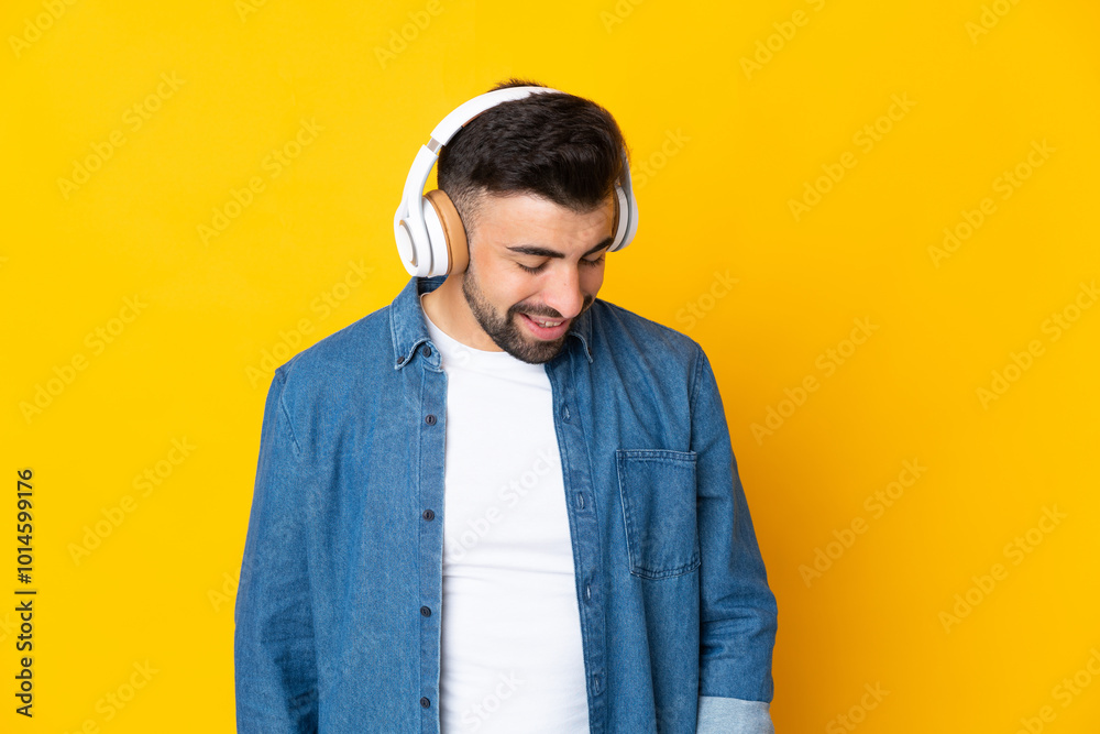 Fototapeta premium Caucasian man over isolated yellow background listening music