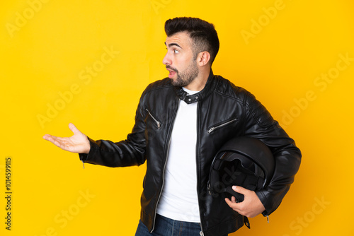 Caucasian man with a motorcycle helmet over isolated yellow background with surprise expression while looking side