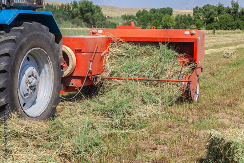 Close up of tractor baling hay using baler on summer day