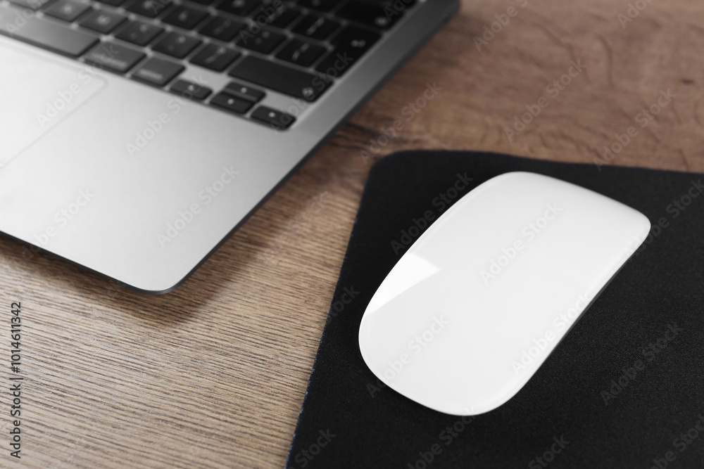 Computer mouse with mousepad and laptop on wooden table Computer mouse with mousepad and laptop on wooden table