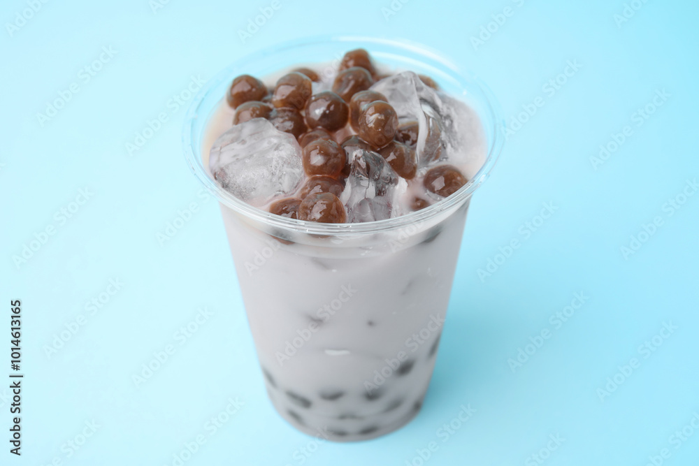 Tasty milk bubble tea in plastic cup on light blue background, closeup Tasty milk bubble tea in plastic cup on light blue background, closeup